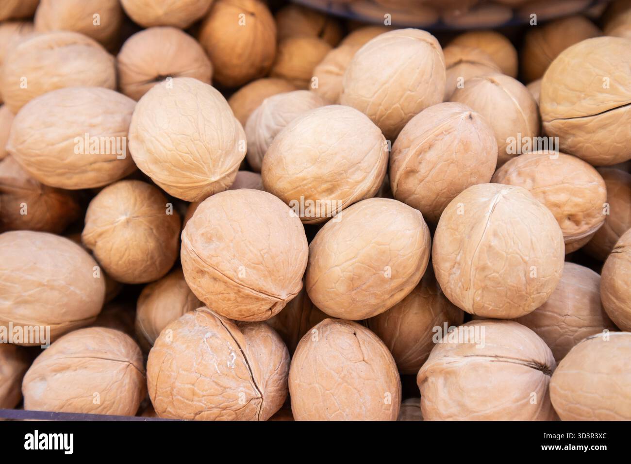 Un'immagine ravvicinata che mostra una pila di noci intere marroni nelle conchiglie naturali. Perfetto per illustrare il concetto di naturale, crudo e nutriziou Foto Stock