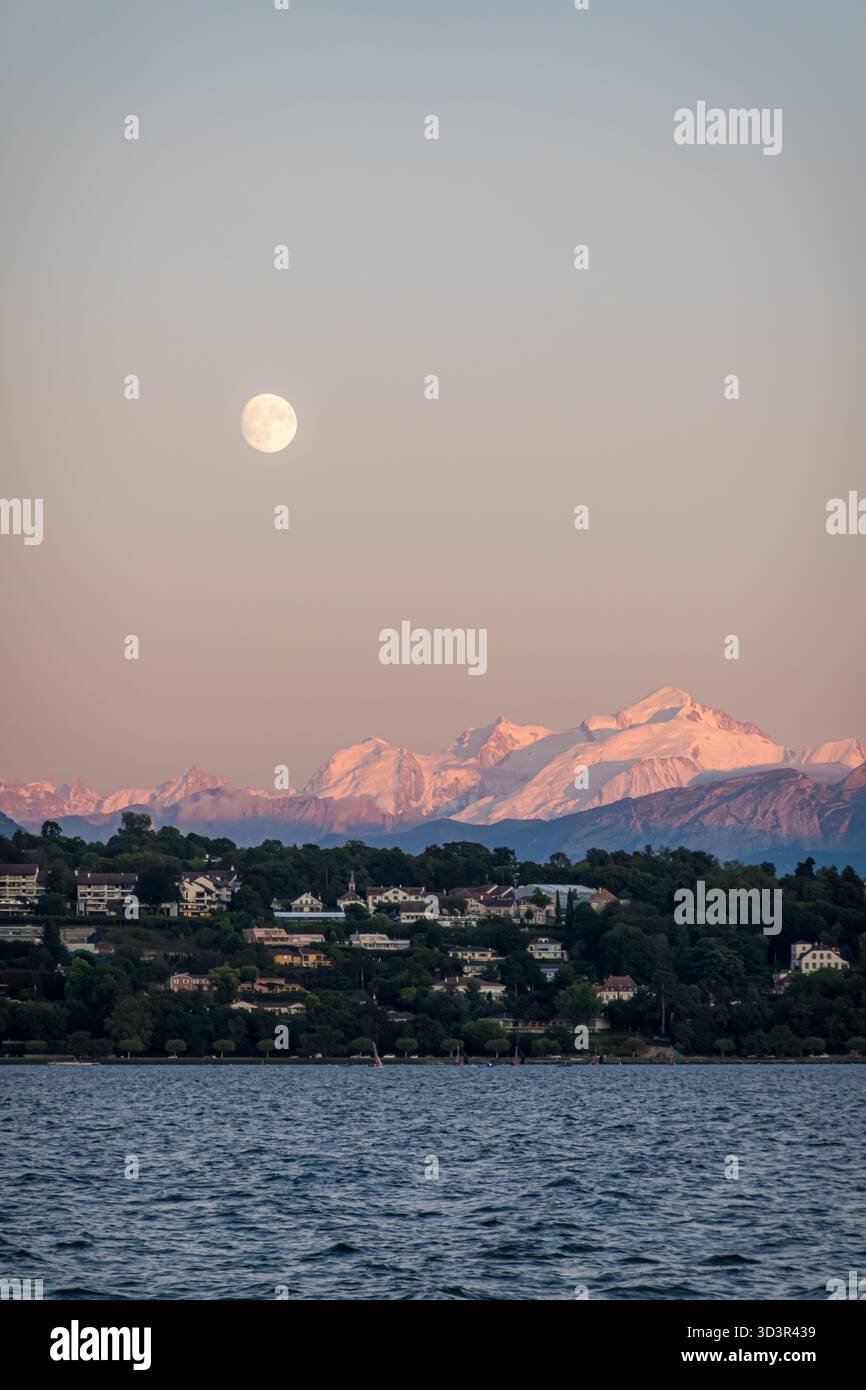 Vista tranquilla del Monte bianco, illuminata dal sole che tramonta, con la luna che sorge sopra. Annidato lungo le rive del Lago di Ginevra, è un mix incredibile Foto Stock