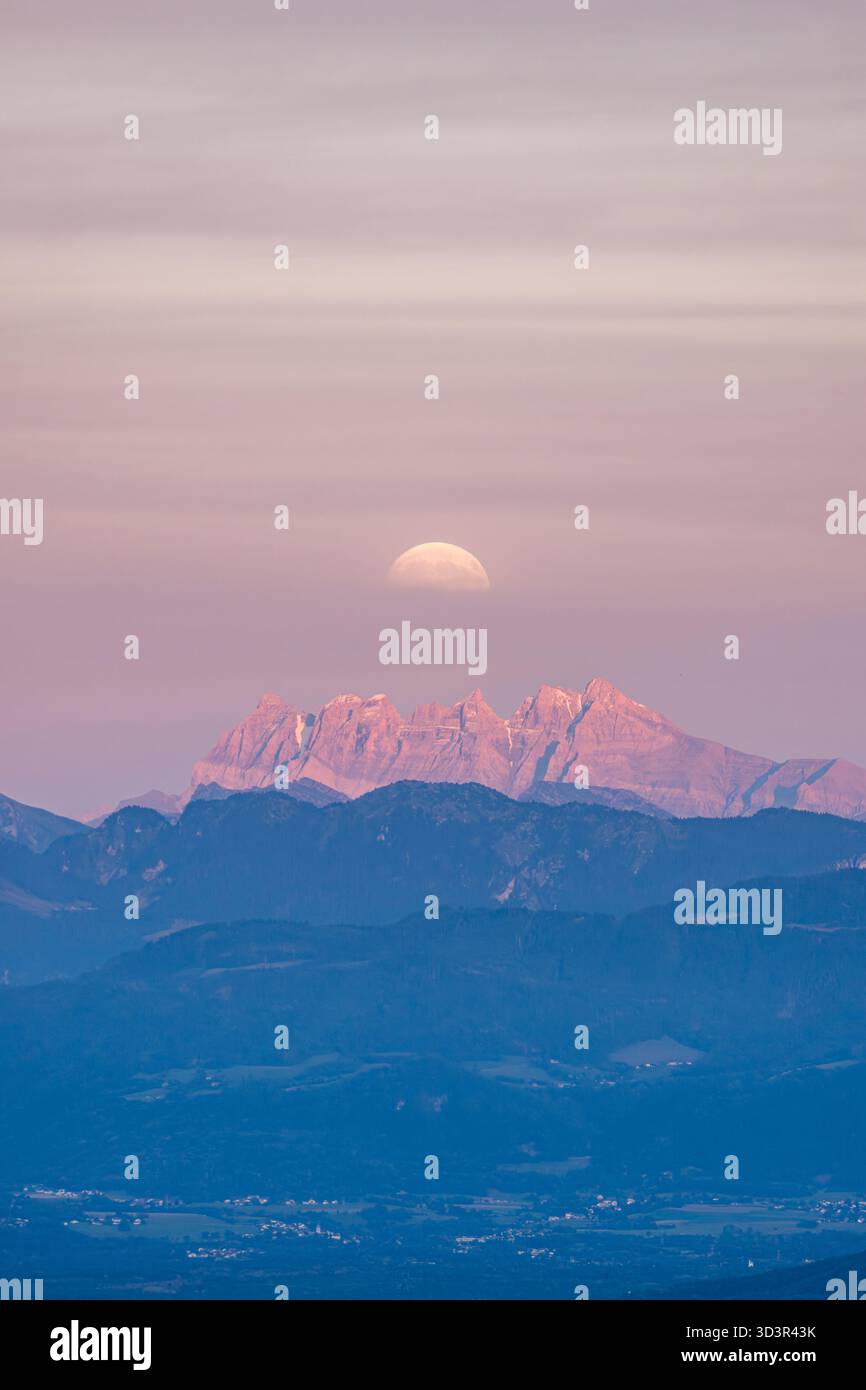 In questa foto accattivante, le sfumature rosa del crepuscolo illuminano le magnifiche Dents du Midi in Svizzera, con la luna graziosamente risi Foto Stock