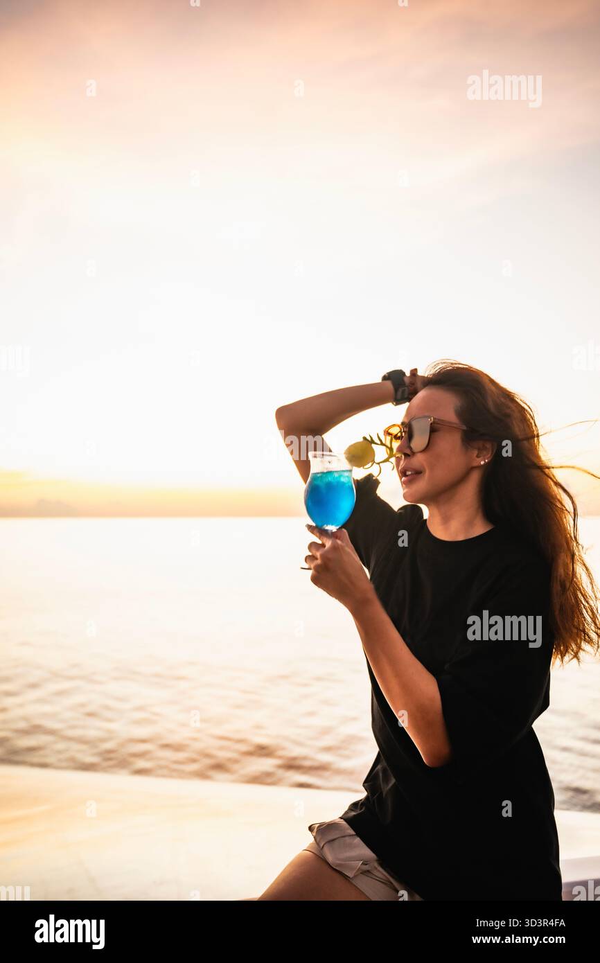 Donna che si diverte con un cocktail alle Maldive Foto Stock