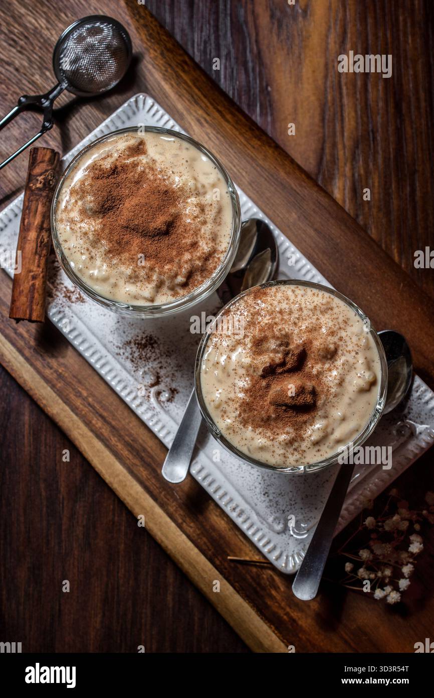 Un delizioso budino di riso fatto in casa condito con un'abbondante spolverata di cannella e un pizzico di scorza di limone. Questo dessert cremoso è perfetto per un'atmosfera accogliente Foto Stock