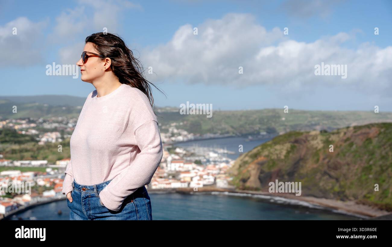 Donna con occhiali da sole che gode della vista da Miradouro da Lira sul Monte da Guia, con Praia do Porto PIM e Monte Queimado come sfondo mozzafiato su fa Foto Stock