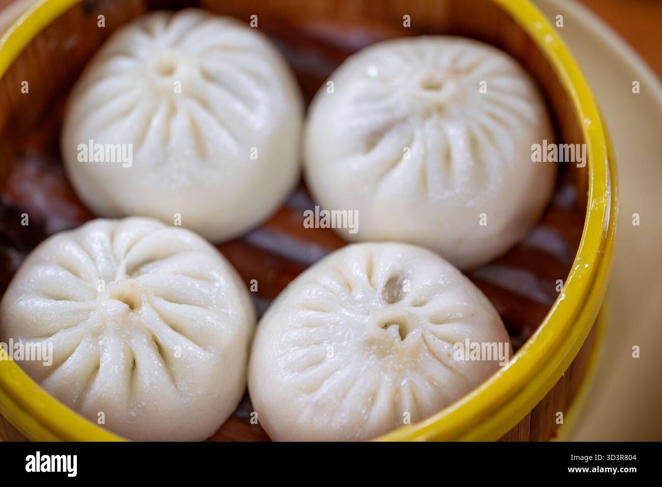 Soffici baozi ripieni di ingredienti salati sono disposti in modo ordinato in una vaporiera di bambù. Questo piatto tradizionale viene gustato a Chengdu, Sichuan durante il pranzo Foto Stock