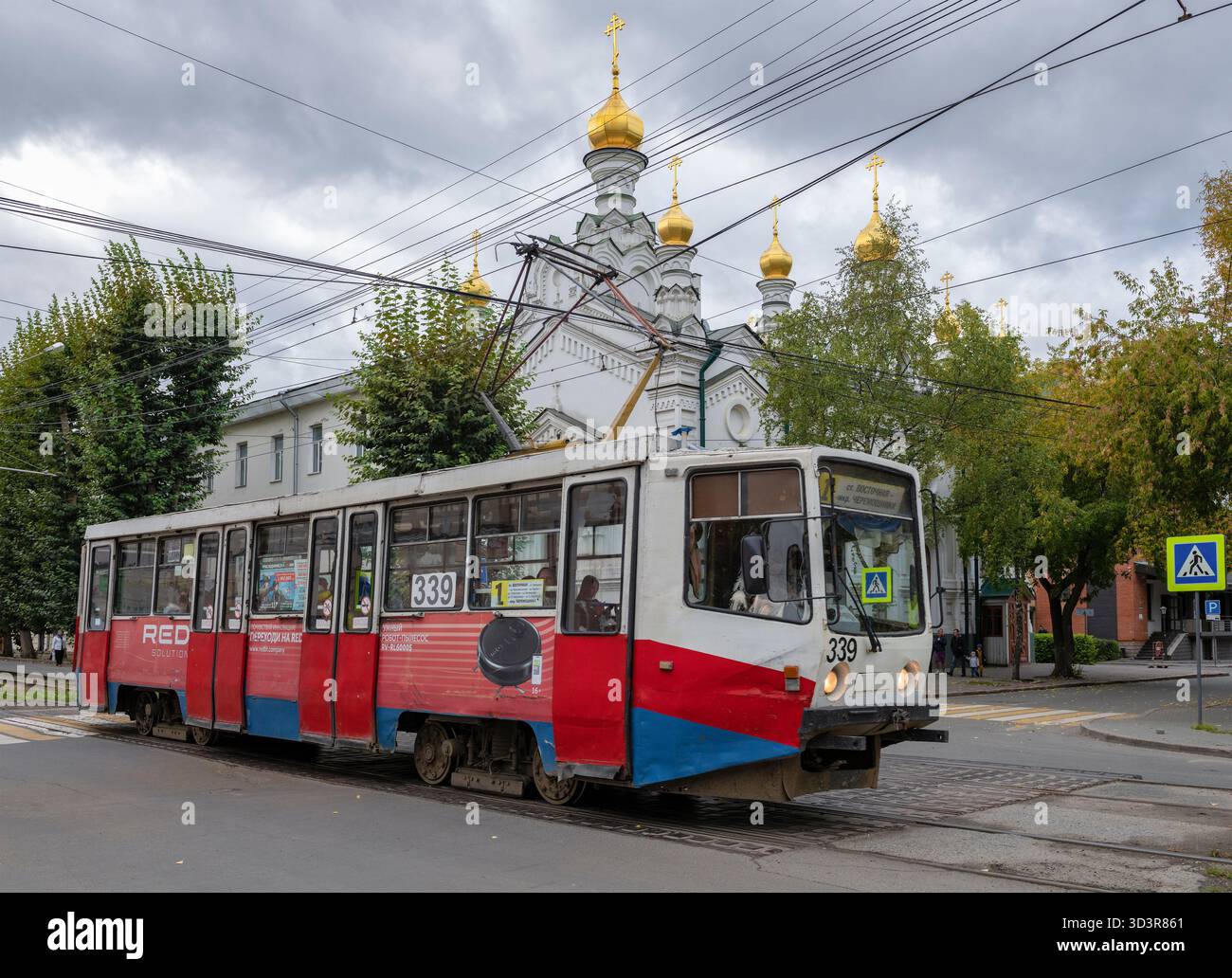 TOMSK, RUSSIA - 14 SETTEMBRE 2025: Tram 71-608KM (KTM-8M) sullo sfondo della chiesa di S. Alexander Nevsky in un nuvoloso giorno di settembre Foto Stock