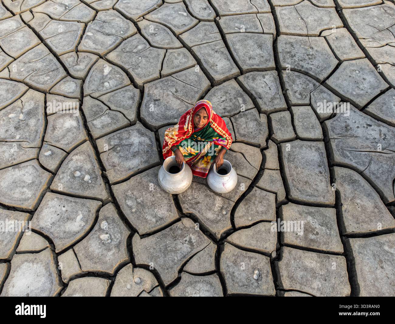 Khulna, Bangladesh - 25 aprile 2025: Veduta aerea di una donna in mezzo a un paesaggio arroccato, vasi di metallo arroccati, un vibrante spruzzo di colore contro la cra Foto Stock
