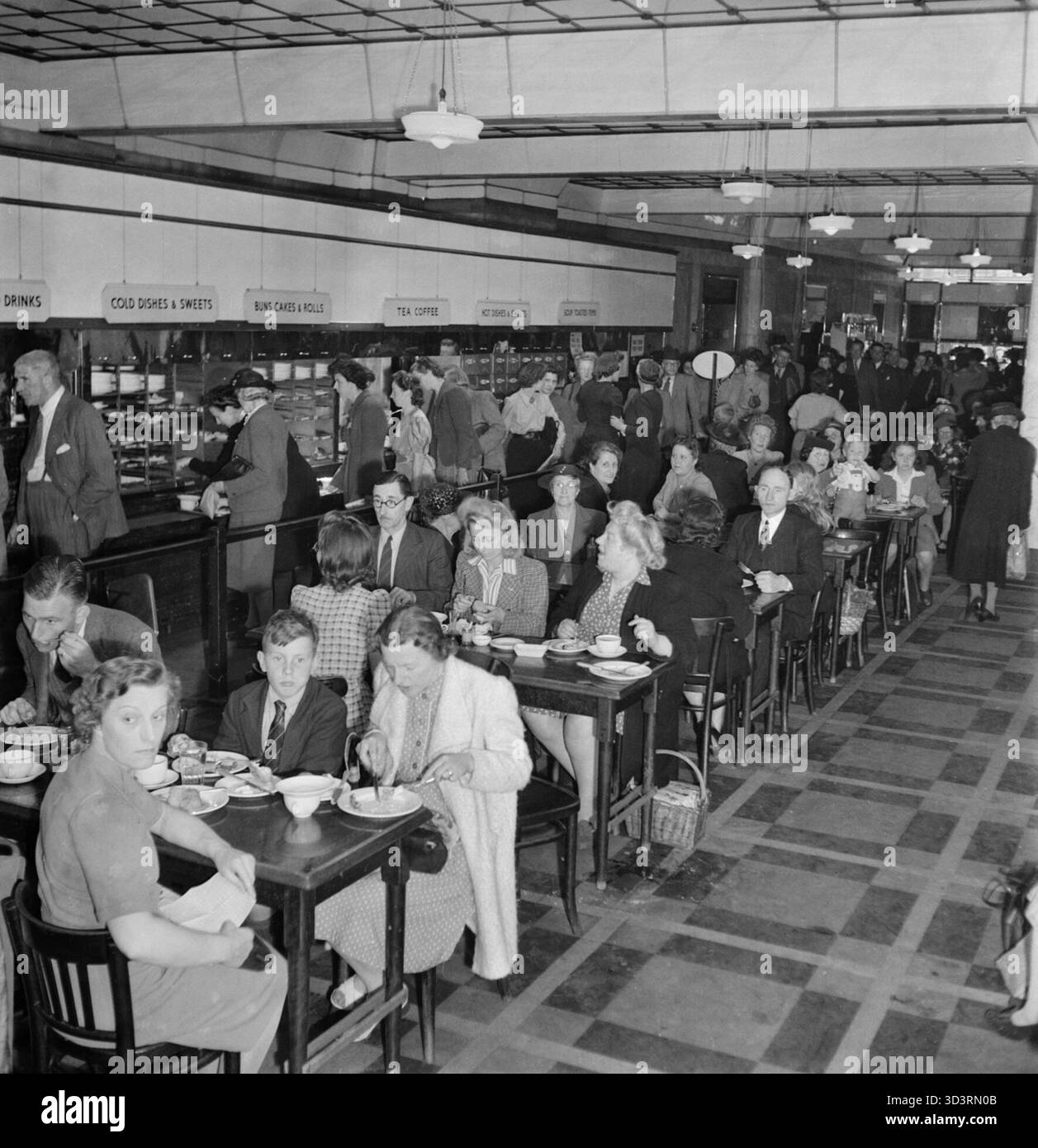 Una foto di una città del Sud - la vita nella lettura in tempo di guerra, Berkshire, Inghilterra, Regno Unito, 1945 uomini e donne si godono un posto per il pranzo al self-service Lyon's Cafe a Reading. In background, il contatore self-service è chiaramente visibile. Qui Foto Stock