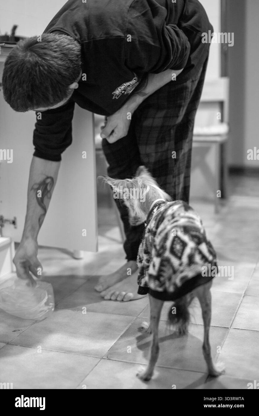 L'uomo e il suo cane vestito condividono un momento tranquillo al chiuso Foto Stock