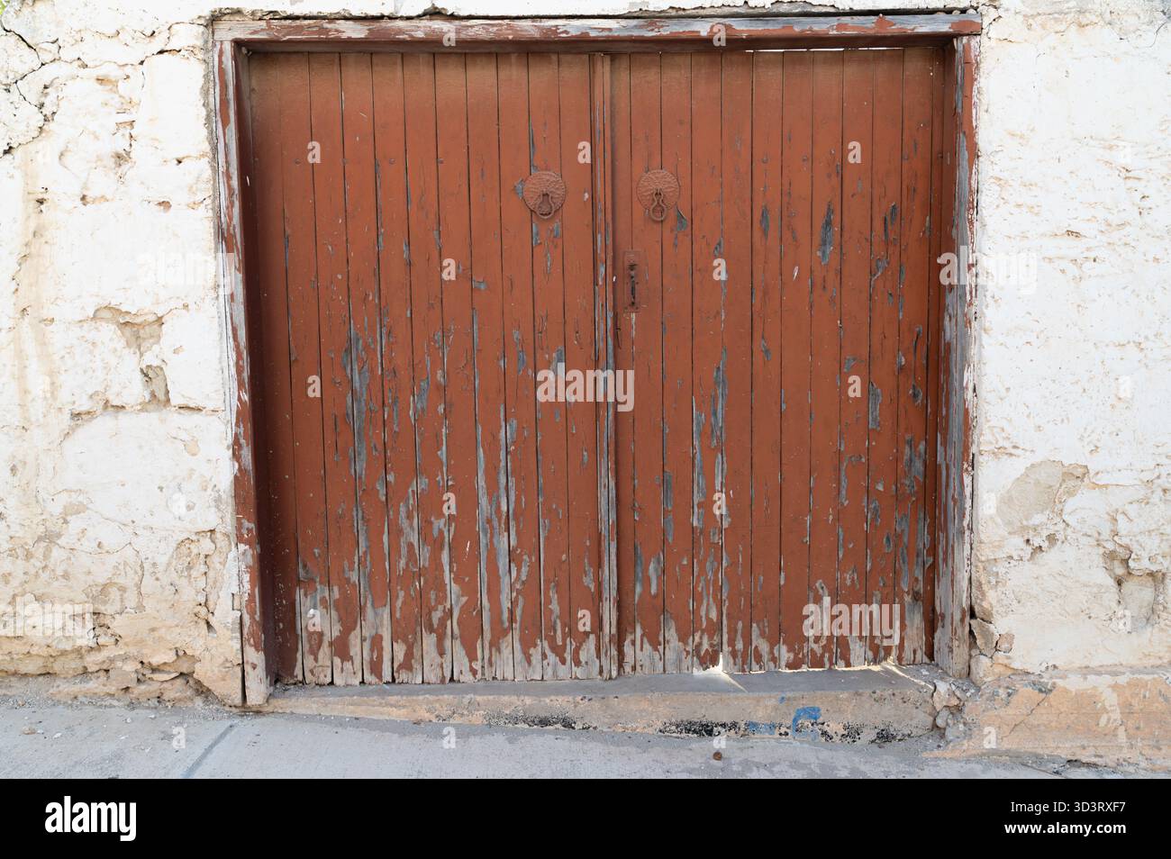 Ambiente rustico del garage, vecchia porta in legno con ombre, porta del garage d'epoca sotto la calda luce del sole, facciata del garage in legno antico con vernice sbiadita e morbida Foto Stock