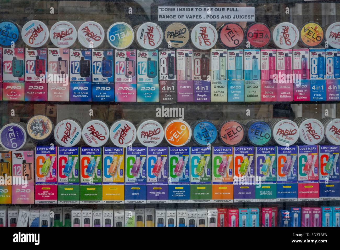 Primo piano di pacchetti colorati di vapori di nicotina e sapori in vetrina. Prodotti e dispositivi di vaping esposti in vetrina colorata Foto Stock
