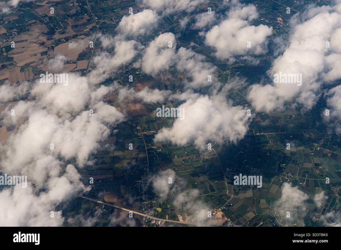 Il cielo è pieno di nuvole e la terra sottostante è per lo più verde. Le nuvole sono sparse in tutto il cielo, con alcune che coprono l'intera area e. Foto Stock