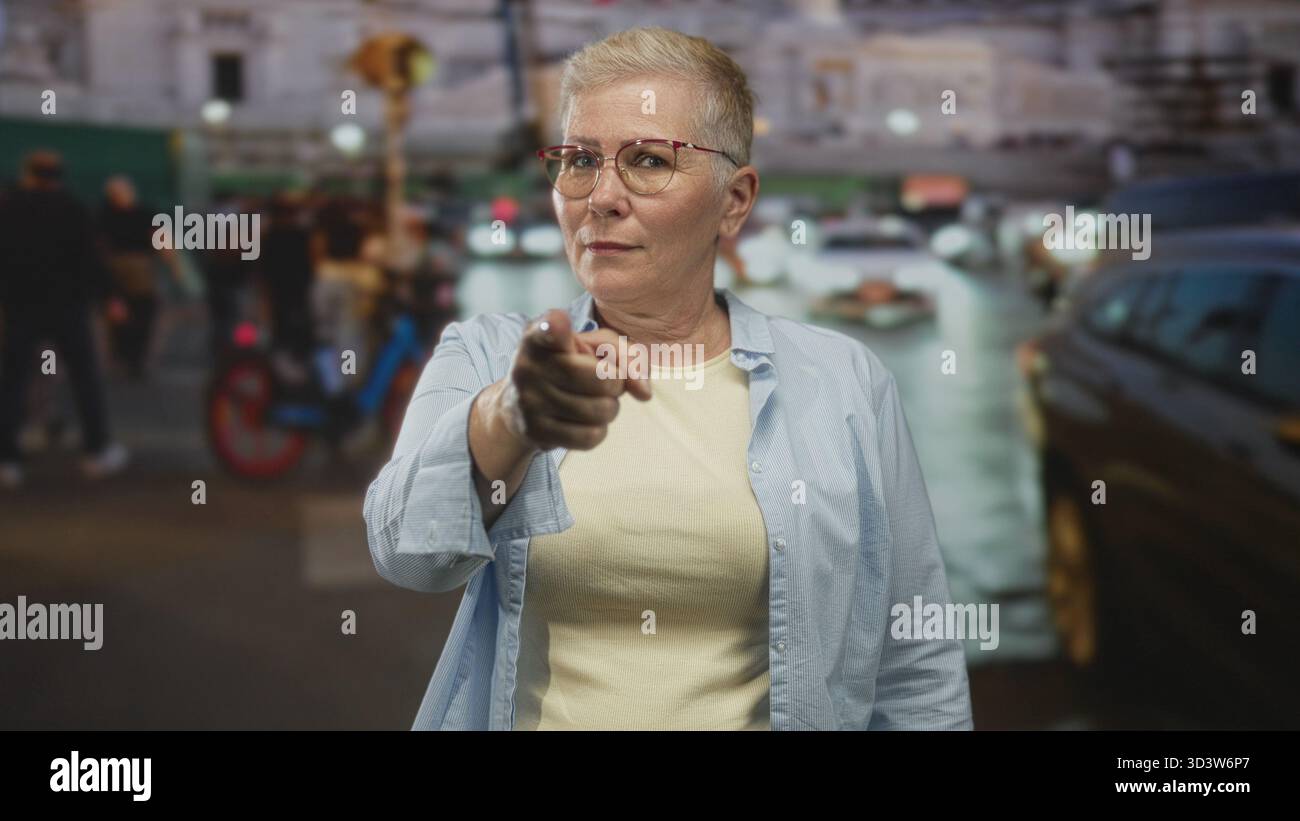 Donna punta il dito contro la telecamera su strade trafficate della città in mezzo al traffico e ai pedoni; comando determinazione. Foto Stock