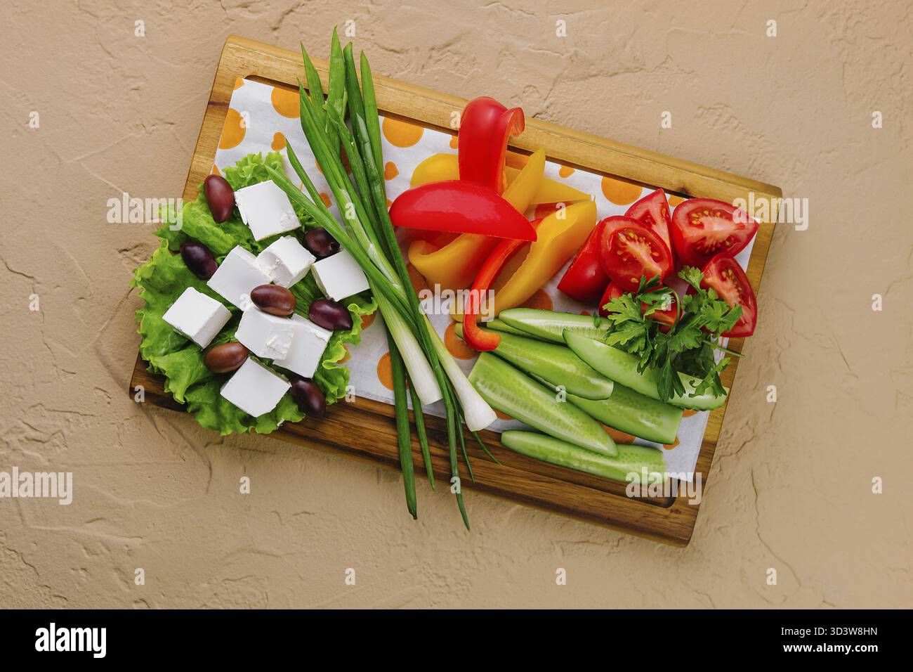 Cibo, cipolle, cetrioli, peperoni, pomodori e formaggio feta con olive su un vassoio di legno Foto Stock