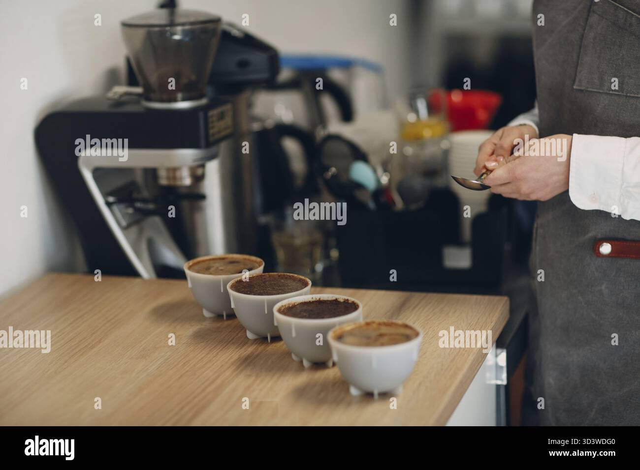 Assaggiatore di tazze donna con cucchiaio in mano prova di qualità del caffè Degustation. Coppetta di caffè Foto Stock