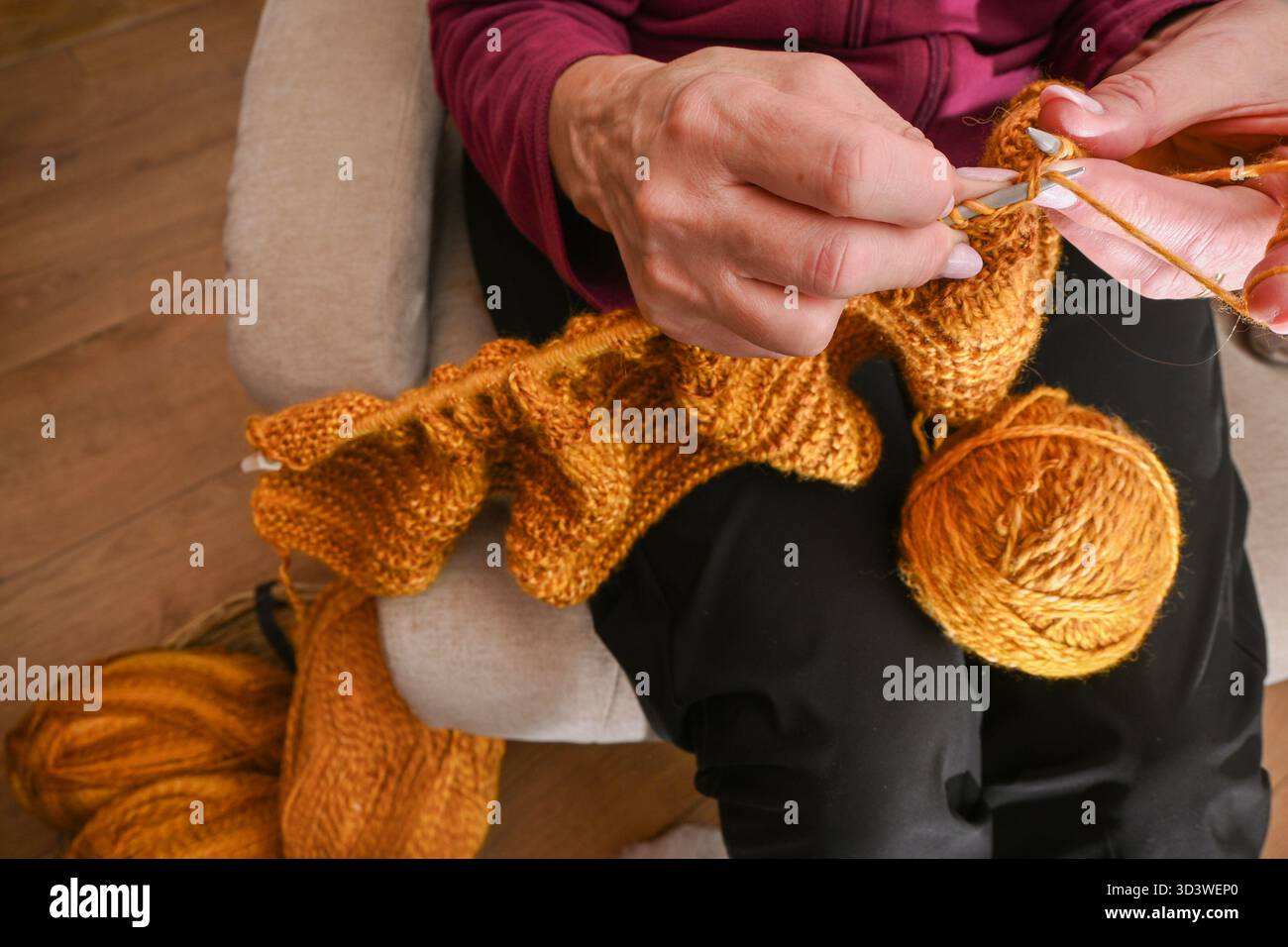 Mani di donna che lavorano a maglia di filati gialli, creando artigianato artigianale. Foto Stock