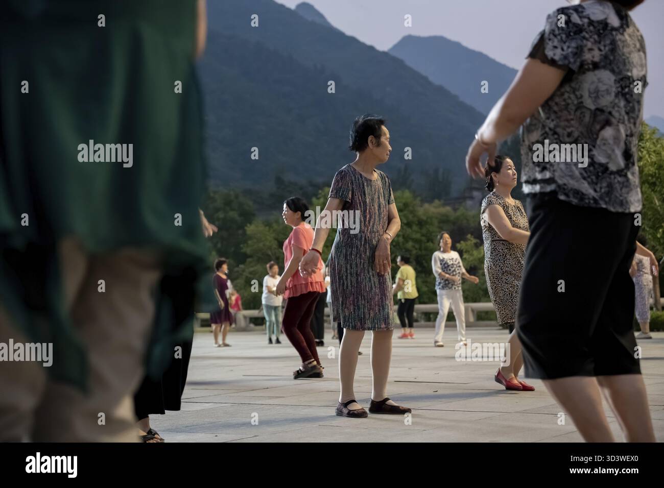 Huashan, Cina - agosto 2019 : gruppo di donne cinesi che ballano nella piazza aperta ai piedi del monte Huashan al crepuscolo, nella provincia di Shaanxi Foto Stock