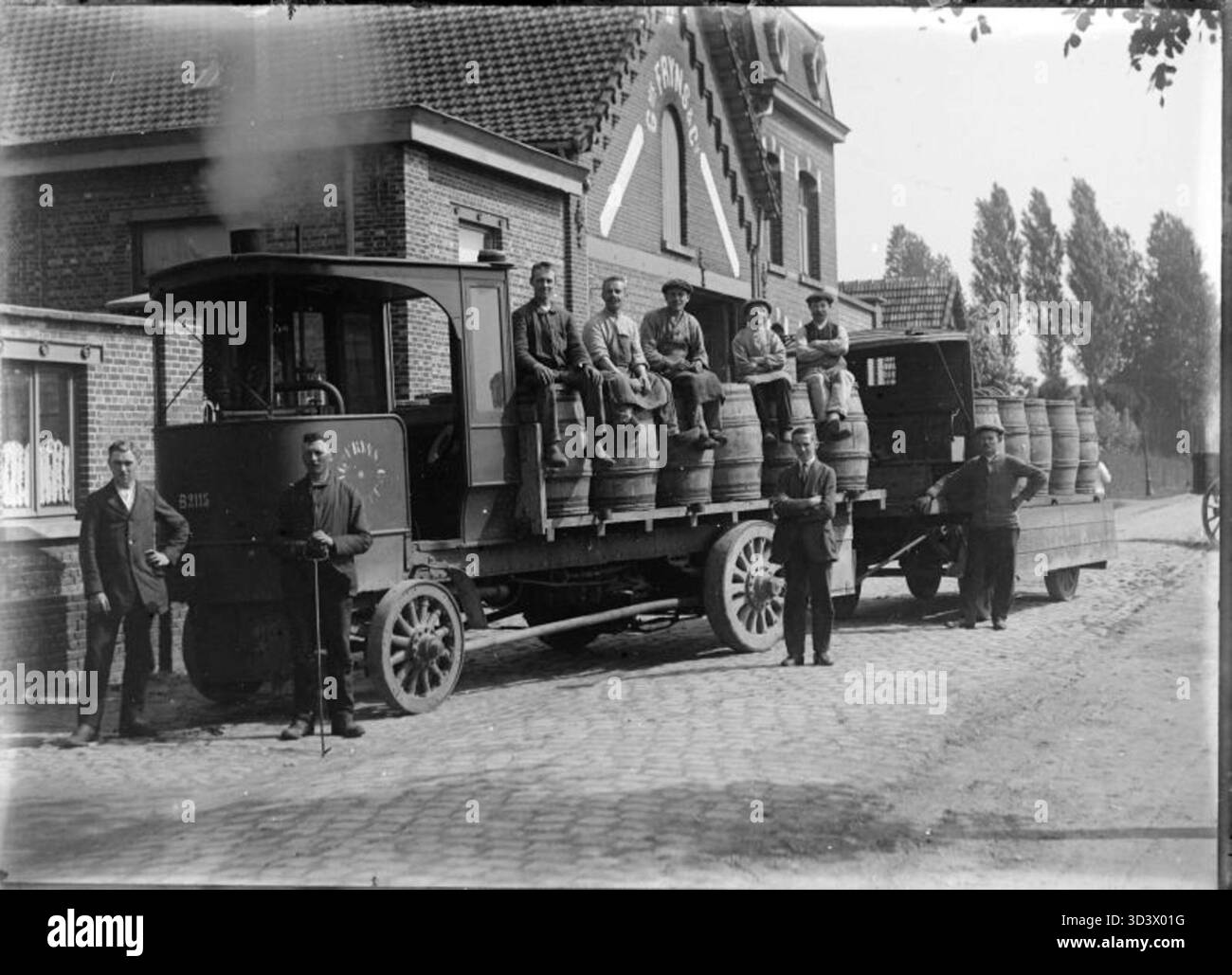 Una lastra di vetro negativa raffigurante i lavoratori che caricano barili su un veicolo di fronte alla distilleria Fryns di Hasselt, intorno al 1930. La foto mette in evidenza la vita industriale del Belgio all'inizio del XX secolo. Foto Stock