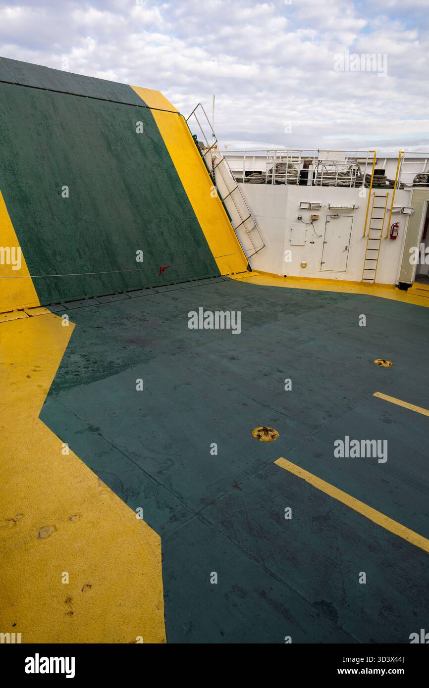 Un ampio ponte navale con marcature di sicurezza verdi e gialle, scale, una porta e una ringhiera. La bulloneria esposta e le superfici intemprate garantiscono una resistenza di m. Foto Stock