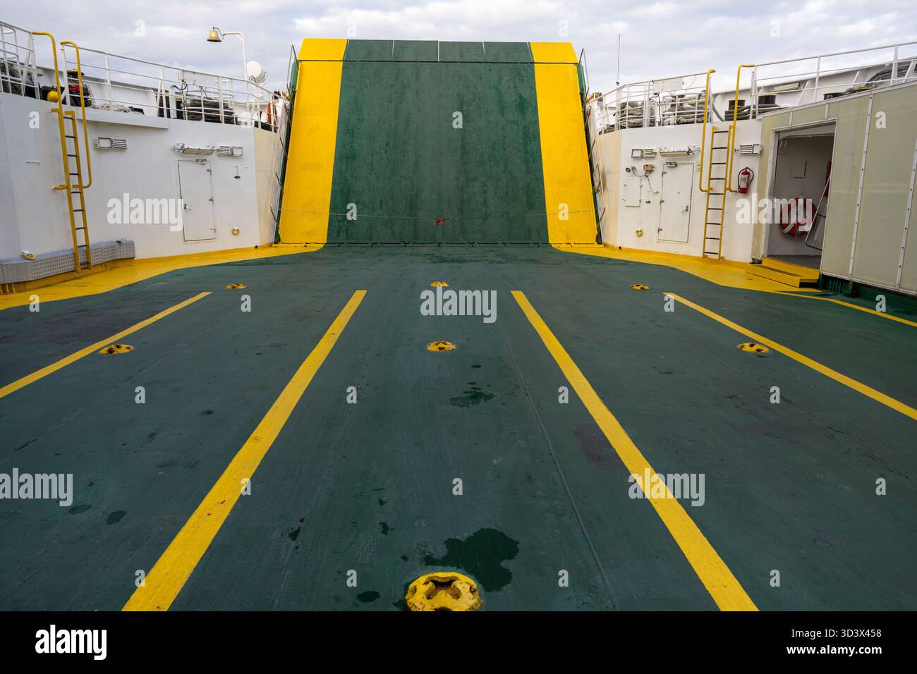 Un ampio ponte navale con marcature di sicurezza verdi e gialle, scale, una porta e una ringhiera. La bulloneria esposta e le superfici intemprate garantiscono una resistenza di m. Foto Stock