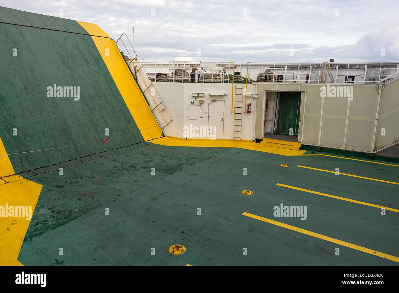 Un ampio ponte navale con marcature di sicurezza verdi e gialle, scale, una porta e una ringhiera. La bulloneria esposta e le superfici intemprate garantiscono una resistenza di m. Foto Stock