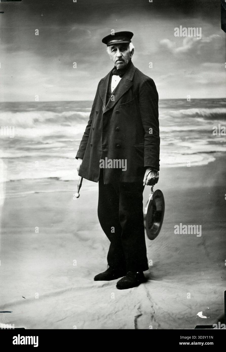 Lange Jan, il piangere della città di Zandvoort, posa di fronte a una spiaggia sullo sfondo per una scena dipinta nel 1914, tenendo il suo gong. Foto Stock