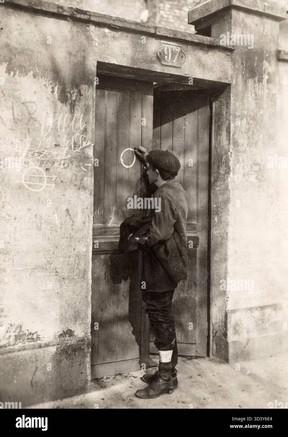 Un uomo disegna un simbolo segreto su una porta, indicando che il cibo può essere trovato all'interno. Questa fotografia, scattata nel 1929, rappresenta le reti informali vaganti create per sopravvivere. Foto Stock