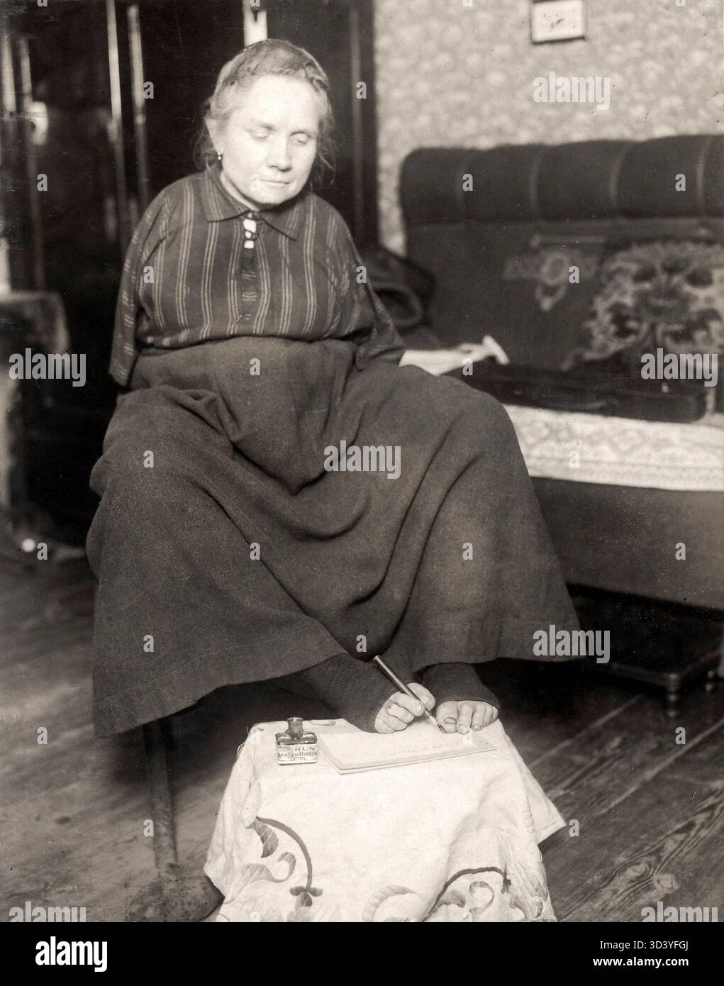 Una donna senza braccia è vista scrivere con i piedi a Berlino, in Germania, nel 1926, dimostrando la sua adattabilità e abilità. Foto Stock
