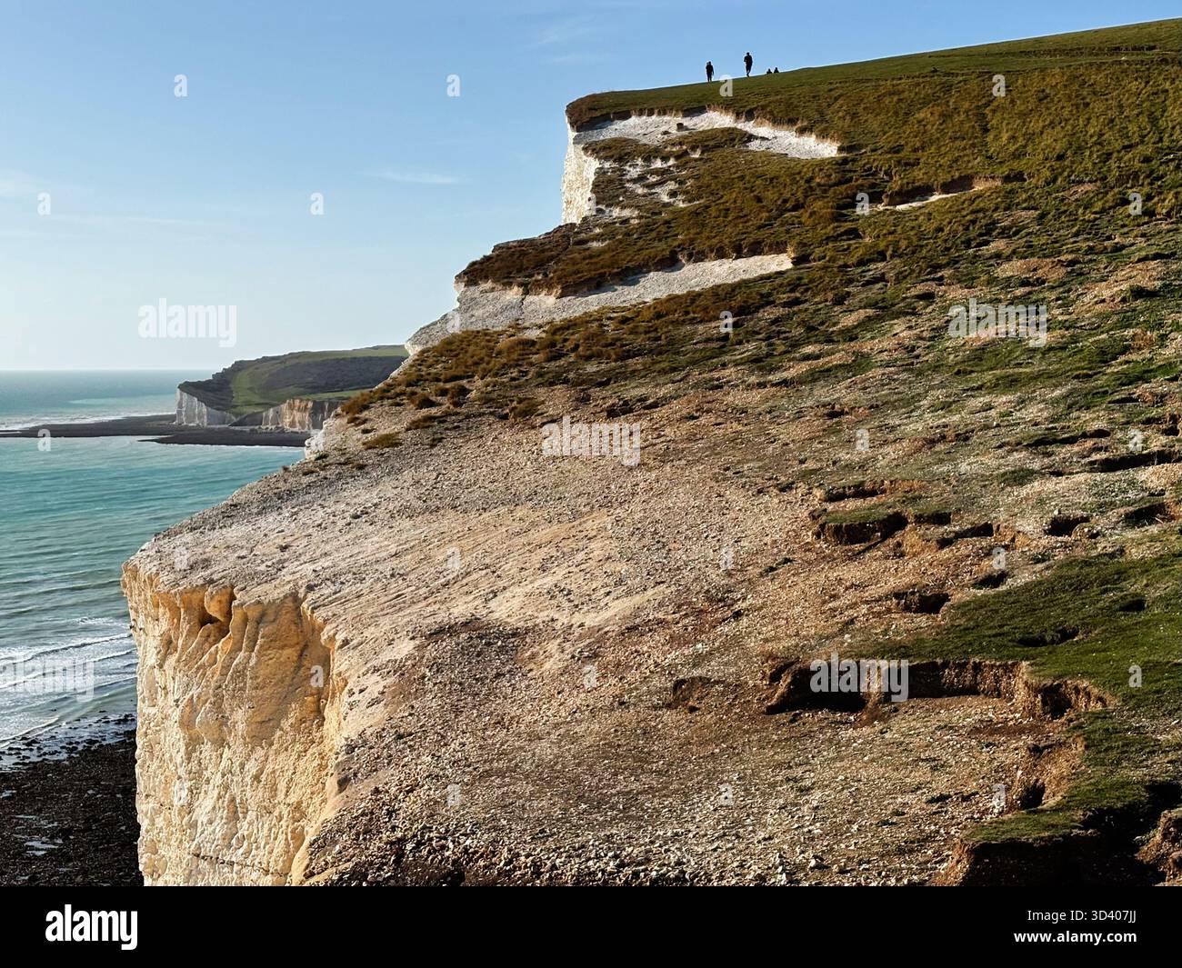 Scogliere e mare lungo le Seven Sisters con escursionisti sul crinale, vista costiera e panoramica nell'East Sussex UK. Foto Stock