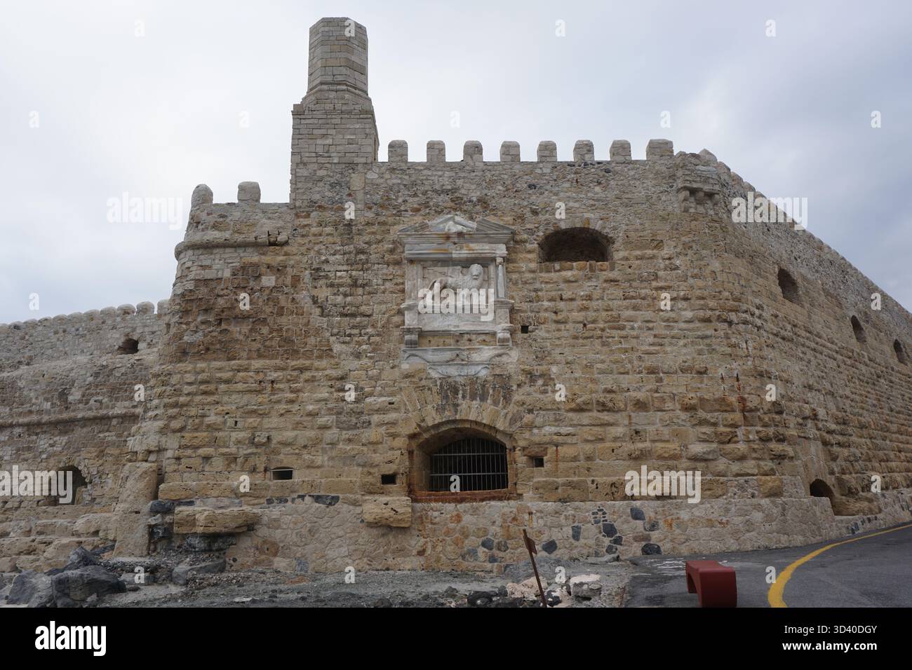 Vista dell'imponente fortezza di Koules con la distinta torre di guardia simile a un camino e il rilievo del Leone di San Marco contro un cielo grigio. Foto Stock