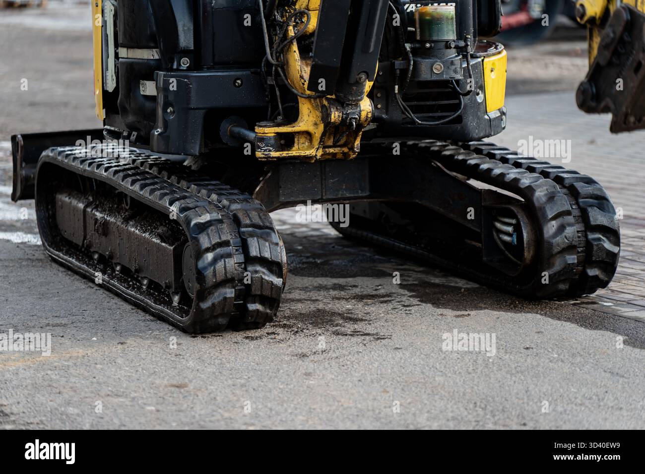 Escavatore compatto con cingoli in gomma parcheggiati su una superficie asfaltata, che rappresenta i moderni macchinari per l'edilizia, le attrezzature per l'ingegneria industriale e il terreno Foto Stock
