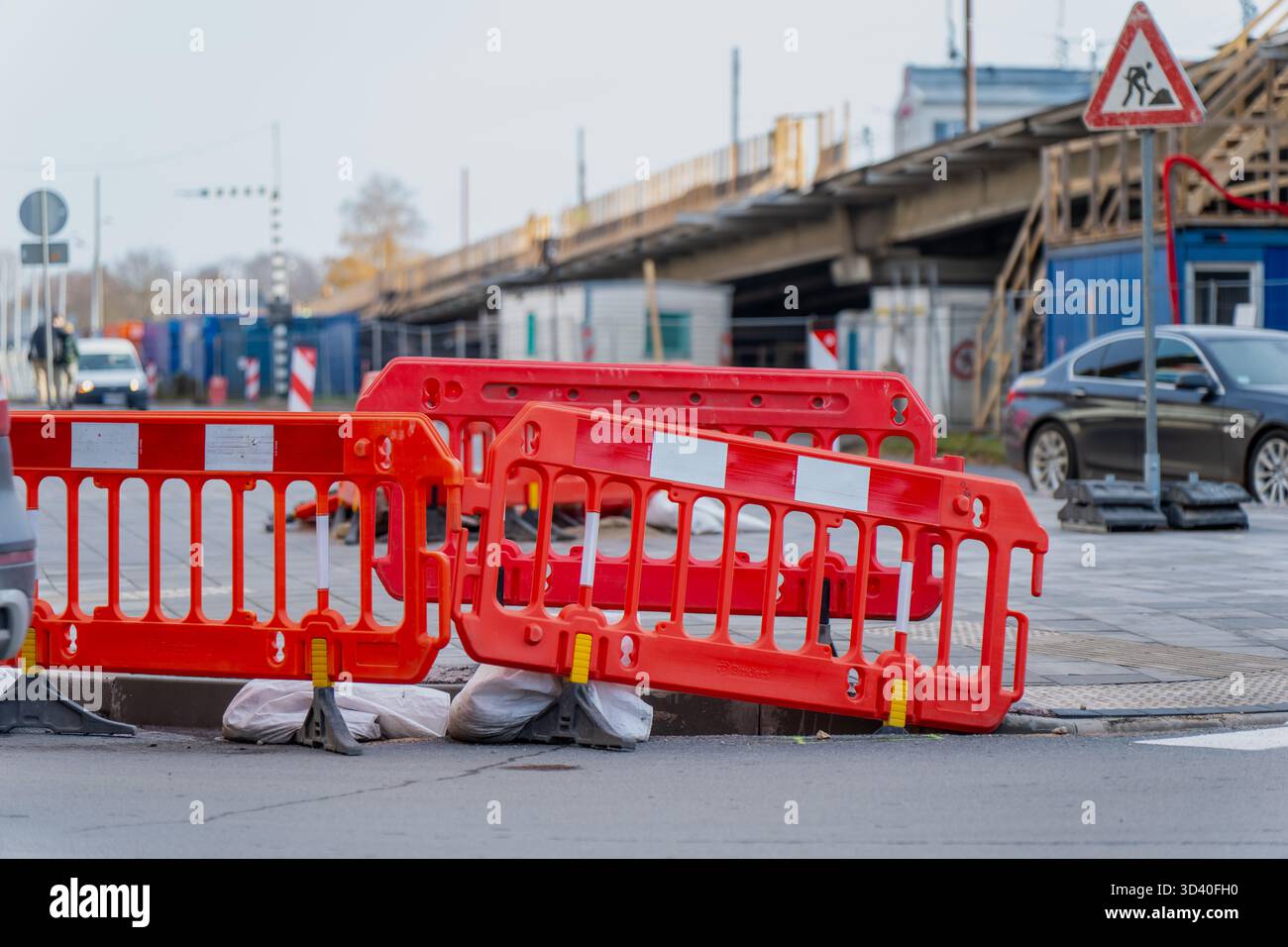 Barriere stradali temporanee nel cantiere di riga, che rappresentano la riparazione delle infrastrutture, il controllo della sicurezza e il lavoro di ingegneria urbana con pedes visibili Foto Stock