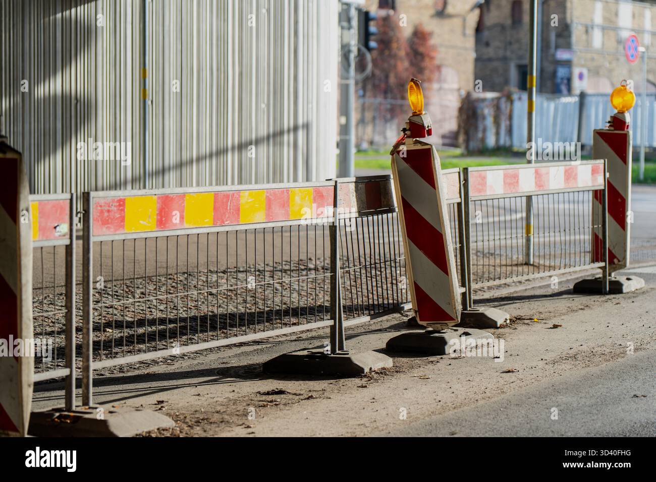 Strada in costruzione con barriere metalliche e pali di sicurezza riflettenti che rappresentano il lavoro infrastrutturale, l'organizzazione della pubblica sicurezza e il tempo Foto Stock