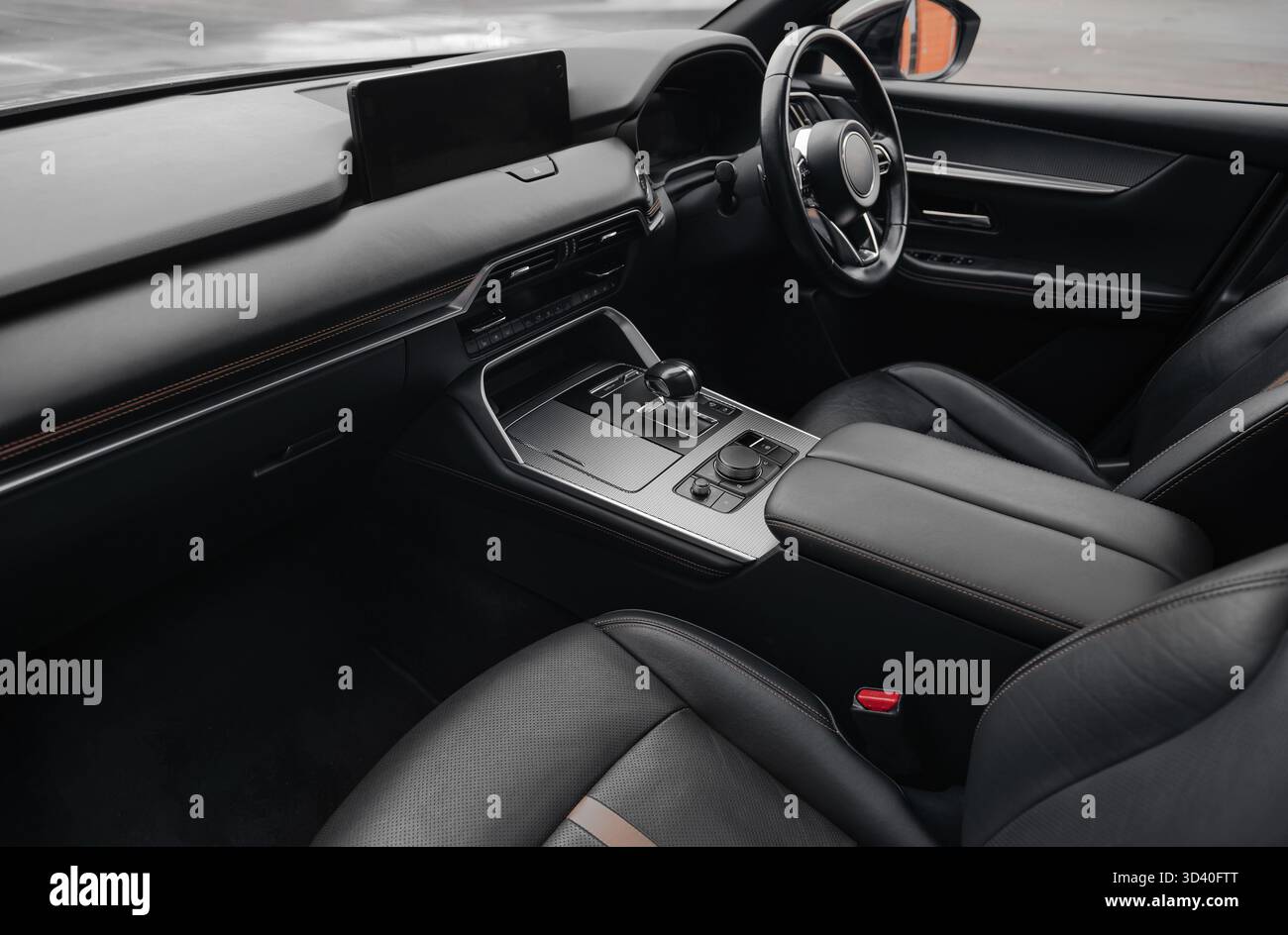 Abitacolo di lusso con guida a destra in pelle nera. Vista grandangolare dell'abitacolo lato passeggero: Sedili, volante, cruscotto, console. Foto Stock