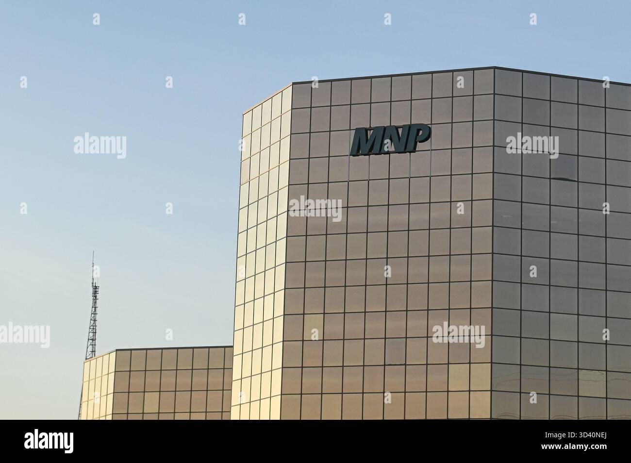 Calgary, AB, Canada - 18 settembre 2025: Un'elegante torre di vetro mostra il logo MNP e la bandiera canadese su un cielo azzurro. Foto Stock