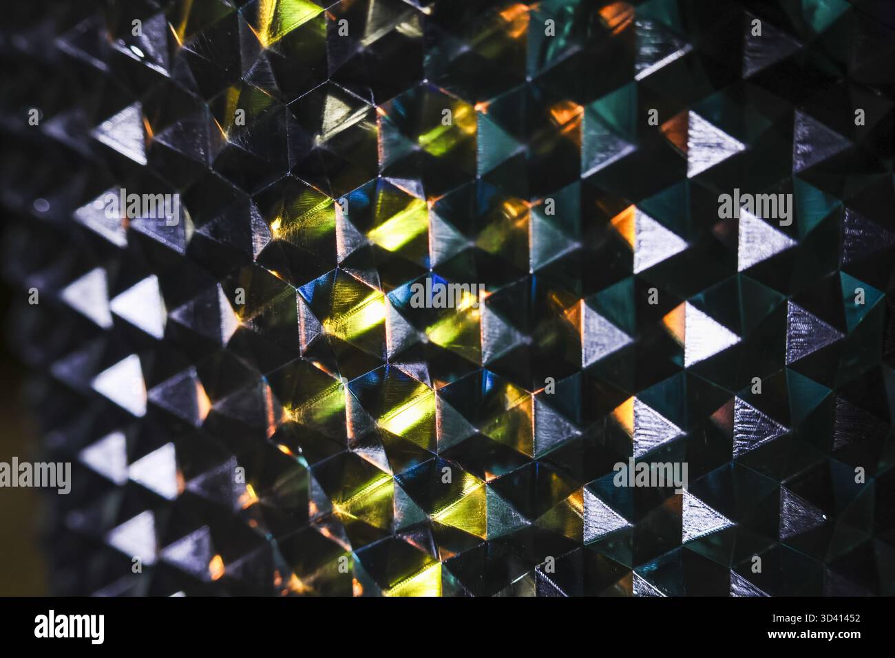 Affascinante primo piano di uno sfondo astratto che mostra un motivo geometrico. la superficie riflettente rifratta la luce in uno spettro colorato, creando un mysteriou Foto Stock
