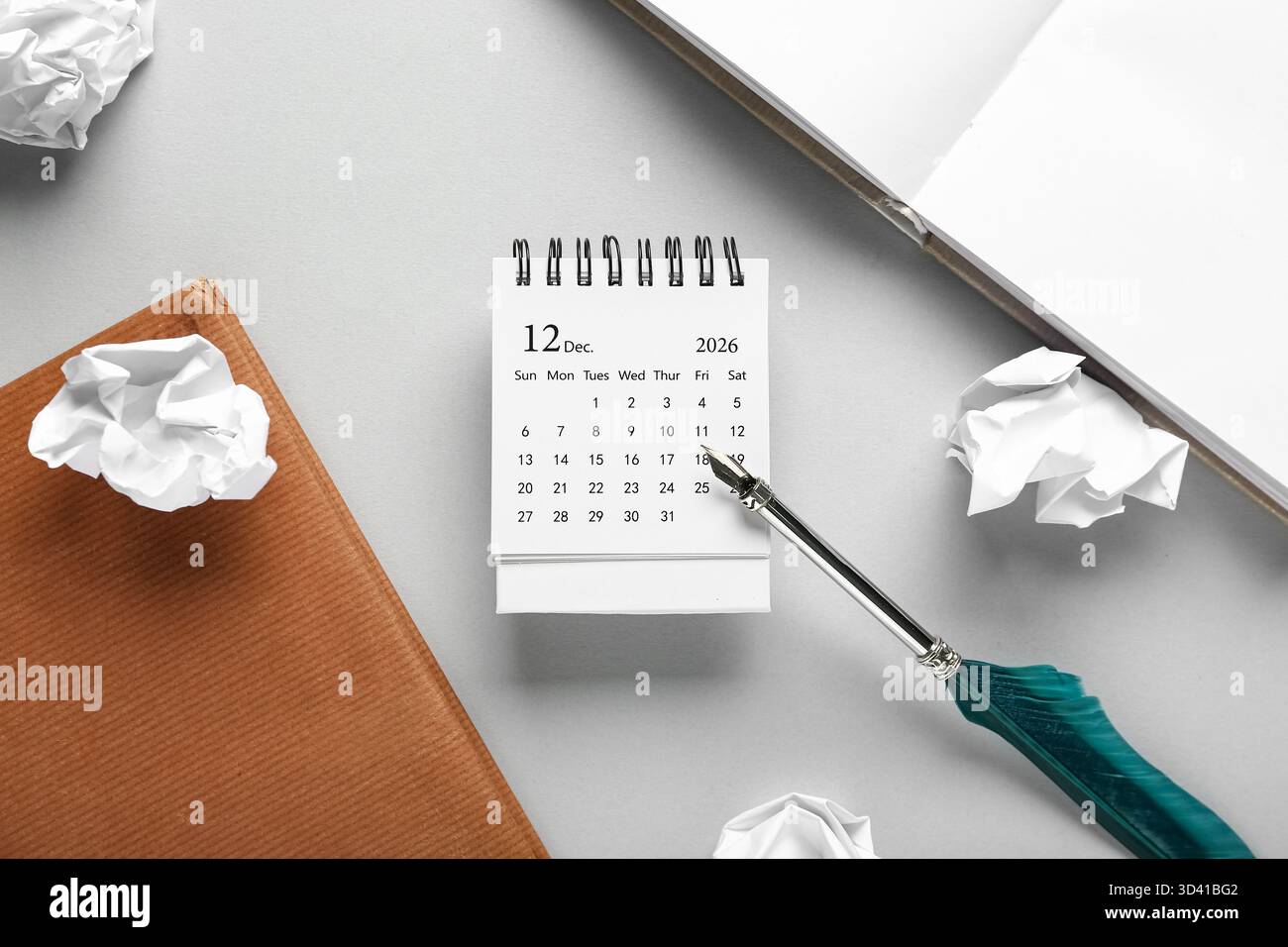 Calendario con piume, libri e carta arricciata su sfondo grigio. Giorno del premio Nobel Foto Stock
