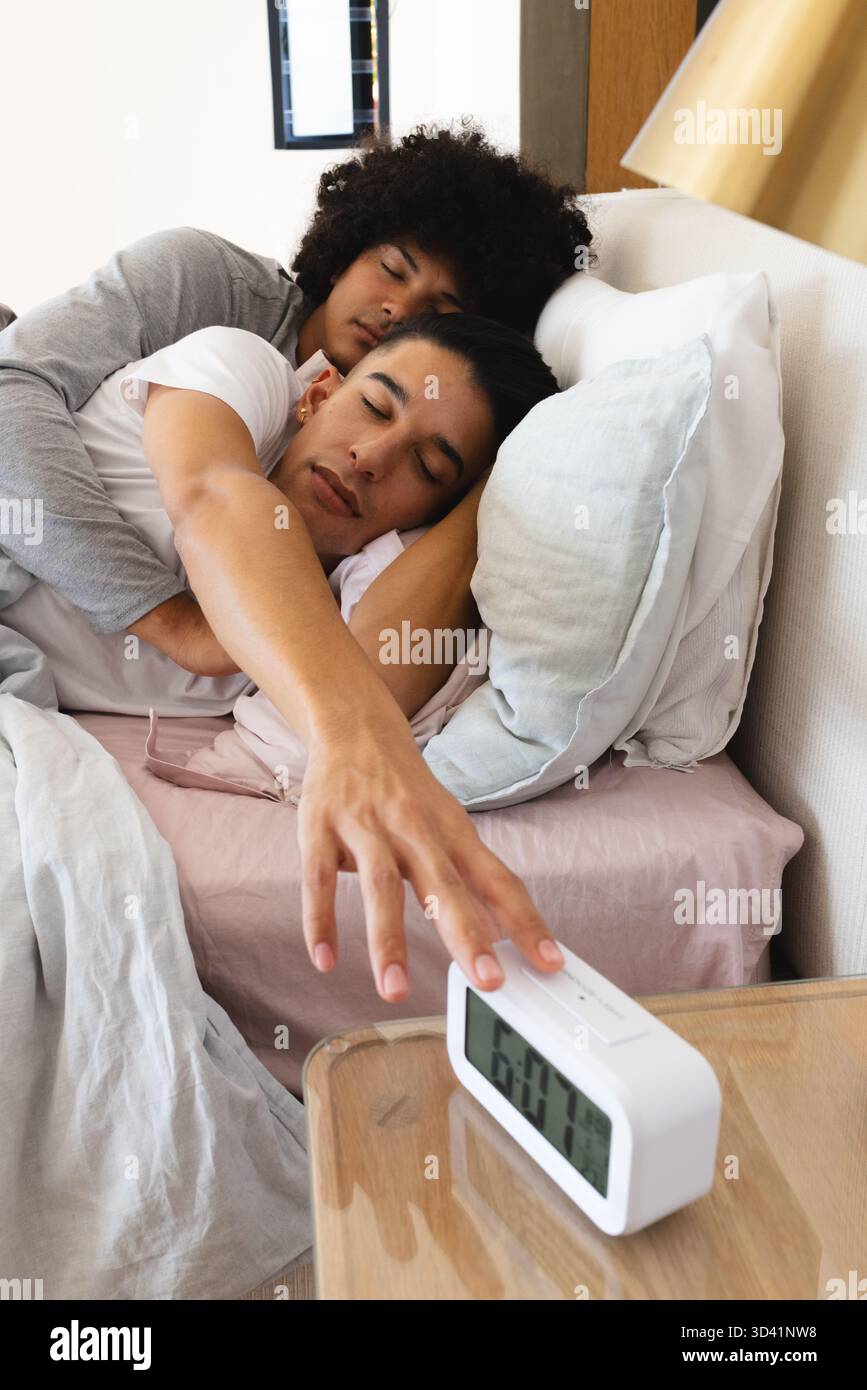 In grado di ospitare due uomini che si spogliano sul letto in una comoda camera da letto, dotata di sveglia digitale e cuscini Foto Stock