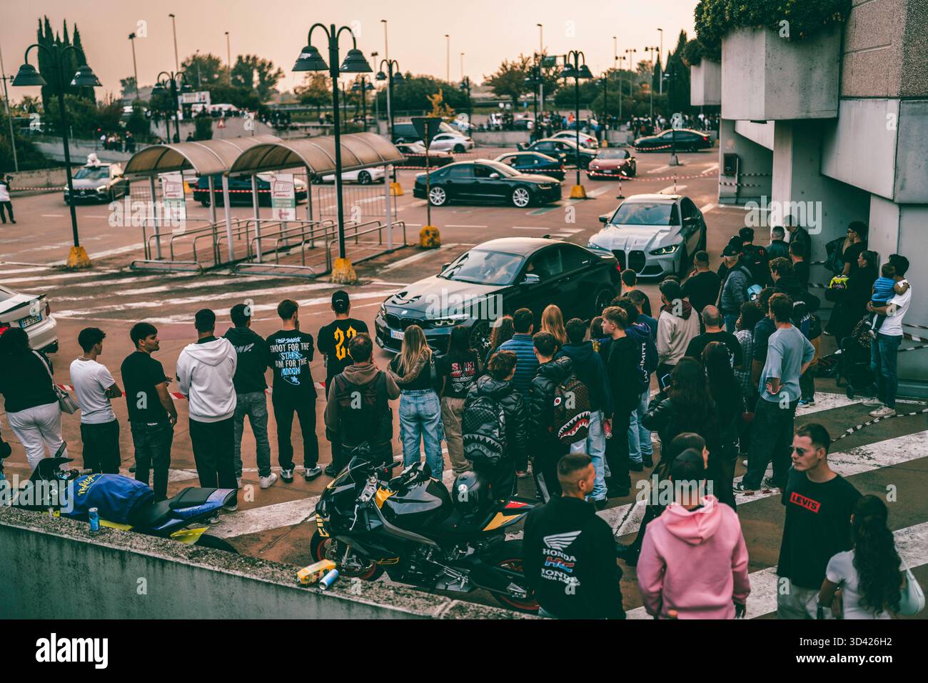 Milano, italia 28 ottobre 2025: Folle di appassionati di auto urbane che guardano gli sport ad alte prestazioni in un vivace Street car Meeting, atmosfera estiva Foto Stock