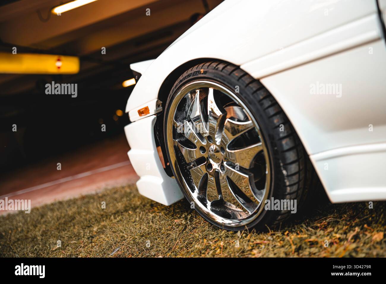 Milano, italia 28 ottobre 2025: Primo piano di un'auto sportiva bianca con cerchi in lega cromata lucida, pneumatici ribassati e eleganti dettagli sul parafango anteriore, MODE Foto Stock