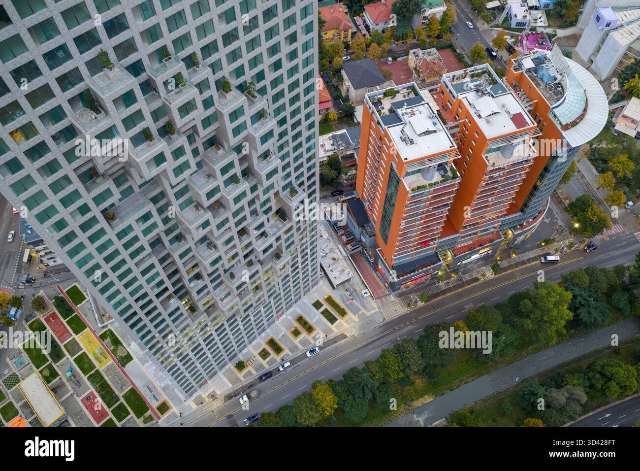 Vista aerea dall'alto verso il basso delle torri residenziali di Tirana, Albania, circondata da alberi autunnali, strade e architettura della città. Foto Stock