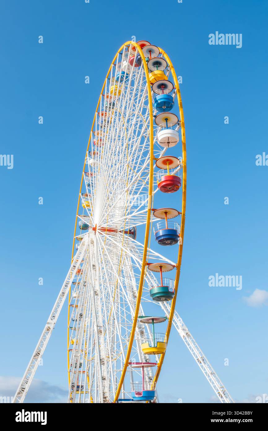 Vista ad angolo basso di una grande e colorata struttura della ruota panoramica su un cielo blu profondo e limpido in una giornata di sole Foto Stock