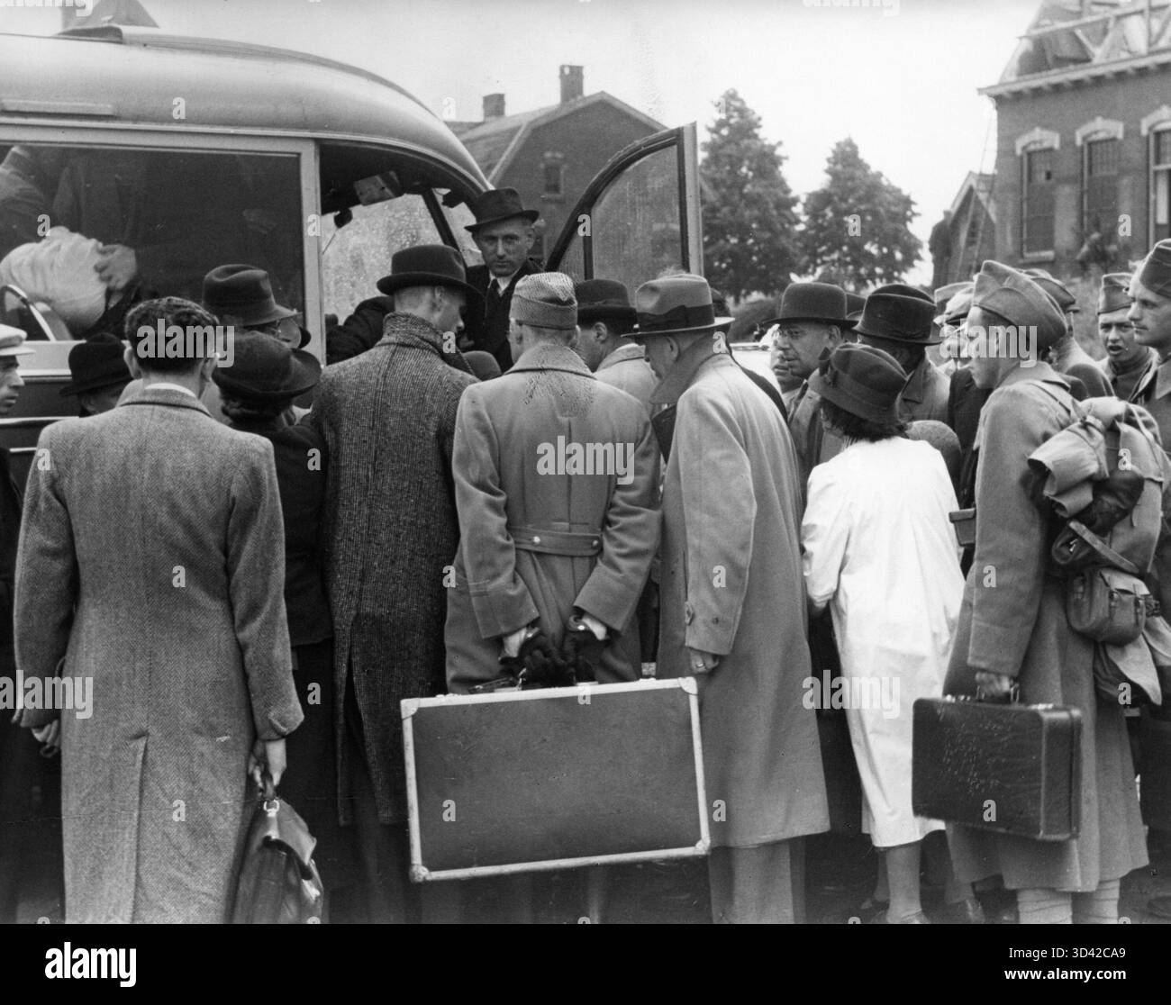 Folle di viaggiatori che salgono a bordo di un autobus a Waardenburg, Paesi Bassi, dopo una lunga attesa a causa della mancanza di mezzi di trasporto disponibili durante la seconda guerra mondiale Foto Stock