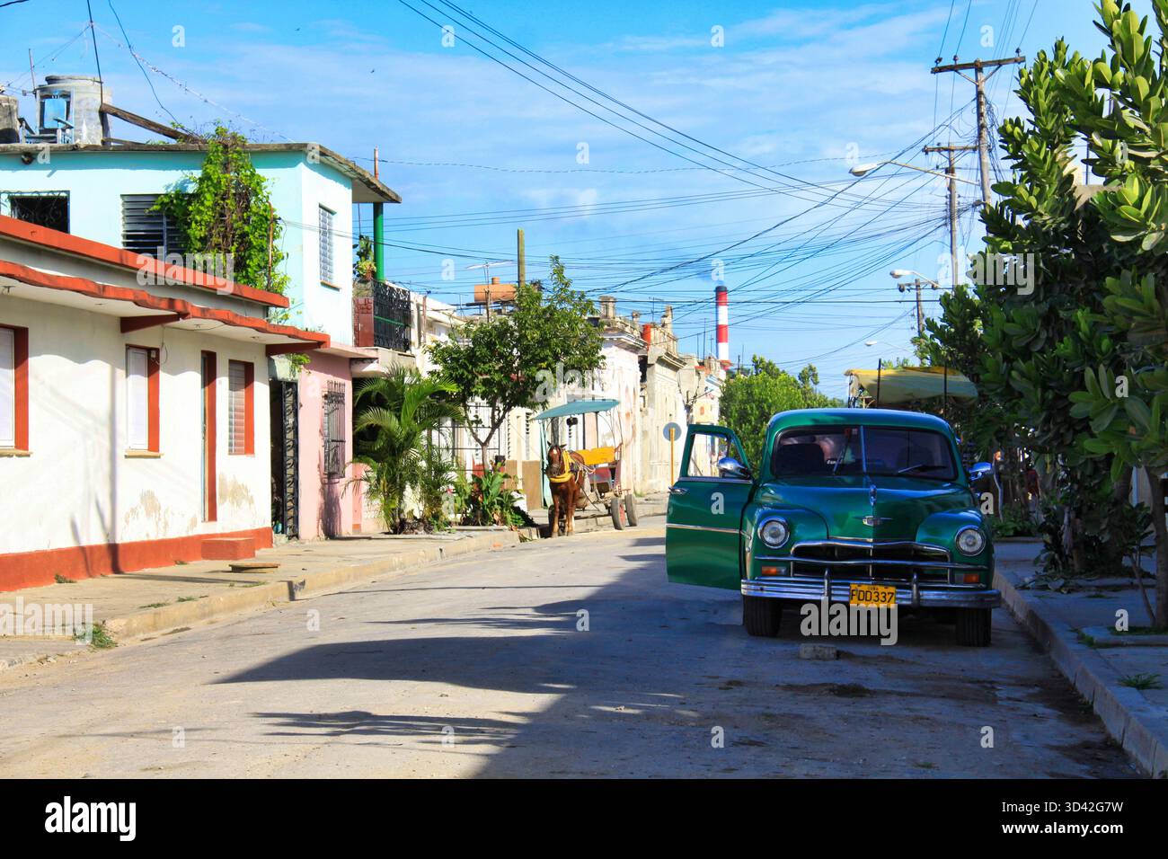 Cienfuegos, Cuba, 12/06/2012 Descrizione: Classic Green Car and Horse-Drawn Cart in a Residential Street in Cienfuegos, Cuba Foto Stock
