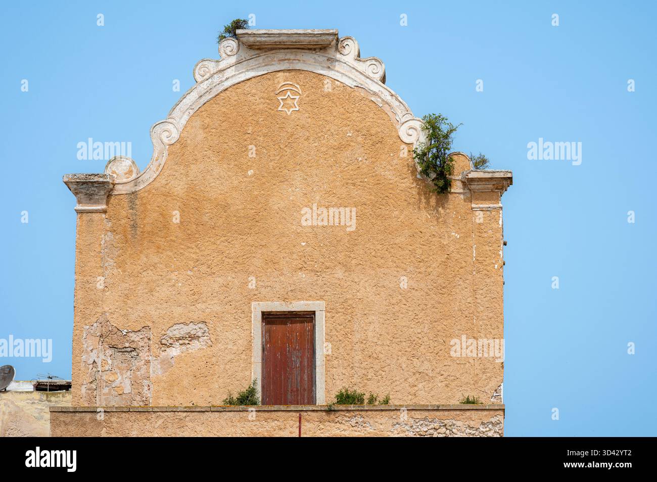 Foto ravvicinata della Sinagoga Bensimon a El Jadida, Marocco, che mostra la sua facciata bianca ornata e i dettagli architettonici sotto la luce soffusa del giorno Foto Stock