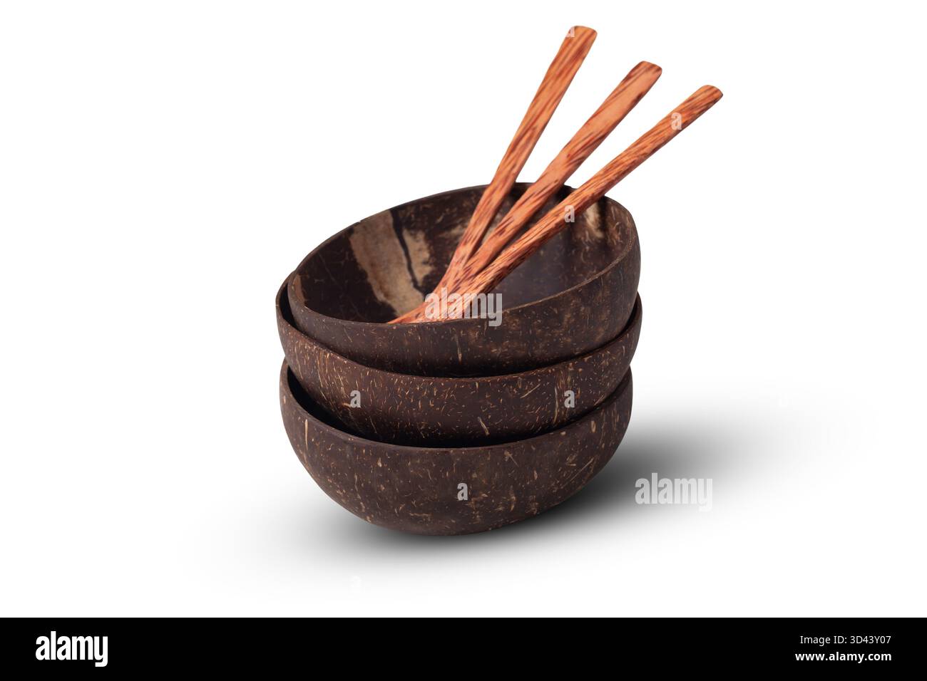 Tre ciotole di conchiglia di cocco di colore marrone scuro, fatte a mano e lucide impilate insieme con tre cucchiai di legno, isolate su uno sfondo bianco Foto Stock