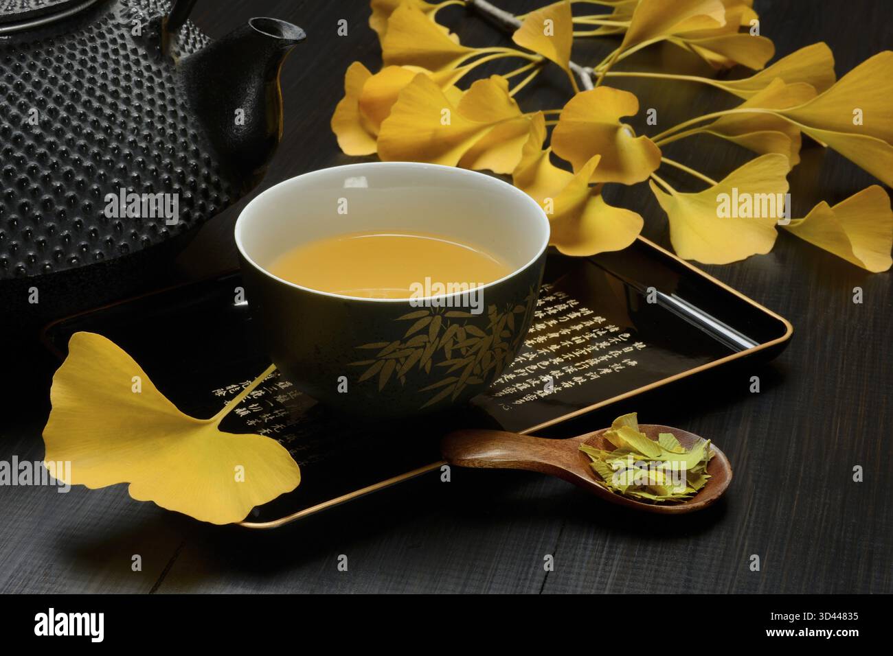 Tè al Ginkgo in una ciotola e foglia di ginkgo, foglie di tè in un cucchiaio, ginkgo biloba Foto Stock