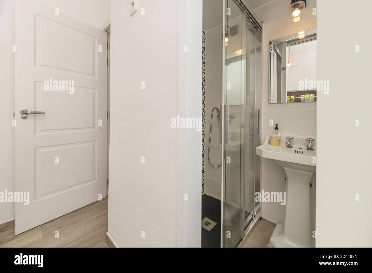 Bagno moderno con doccia curva ad angolo, sistema di cromoterapia e rivestimento in pietra naturale nelle tonalità del grigio neutro Foto Stock