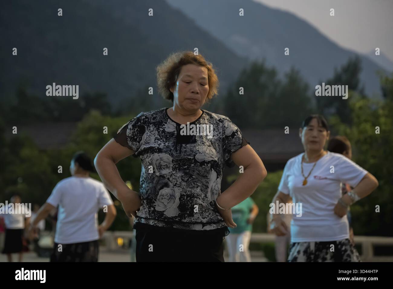 Huashan, Cina - agosto 2019 : gruppo di donne cinesi che ballano nella piazza aperta ai piedi del monte Huashan al crepuscolo, nella provincia di Shaanxi Foto Stock
