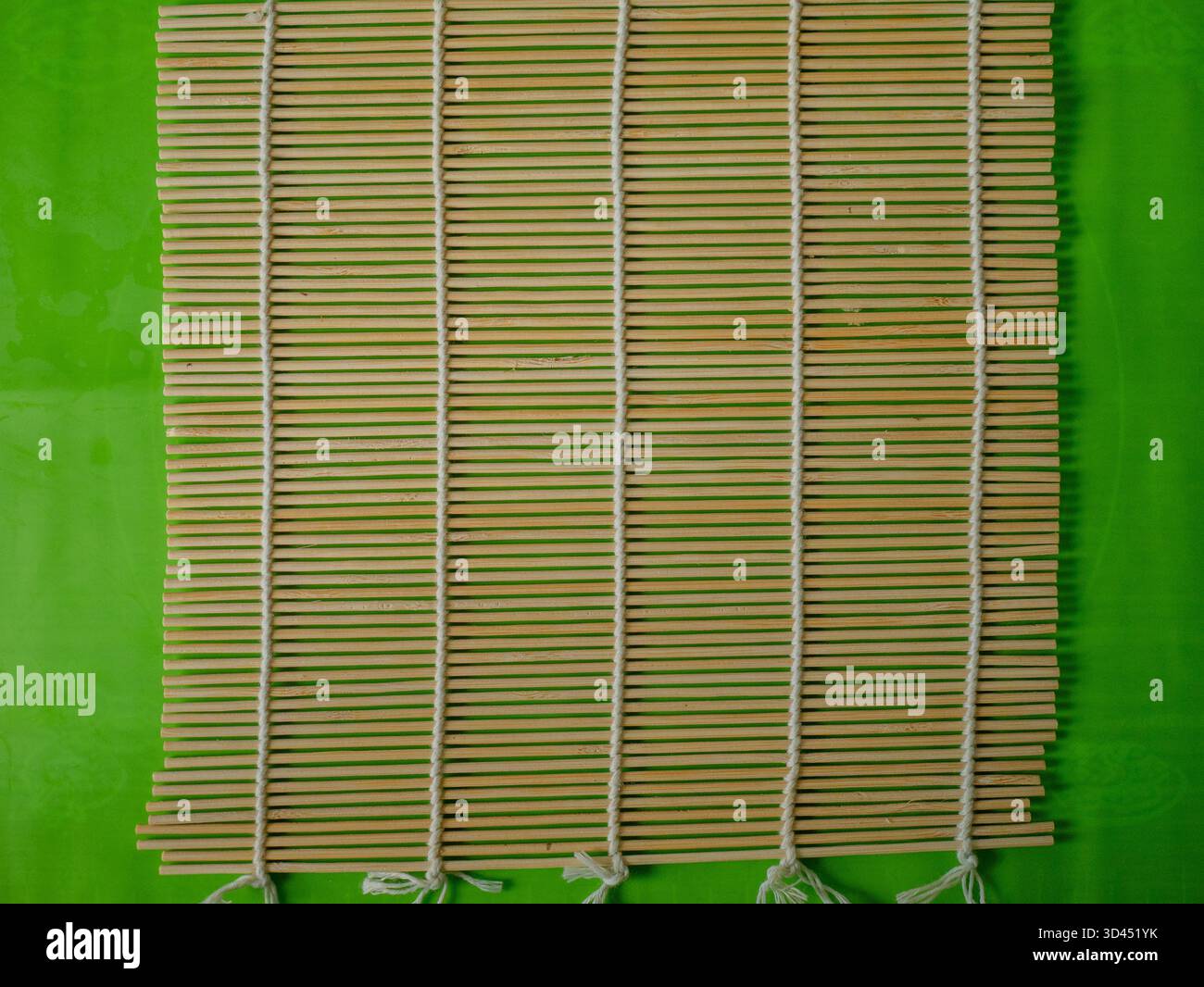 Vista dall'alto del tappeto di bambù vuoto su sfondo verde pronto per il sushi Rolling, preparazione della cucina giapponese foto per cucina e creatori di cucina. Foto Stock
