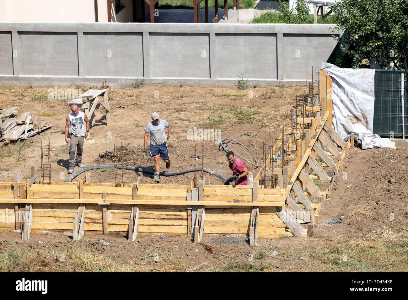 Il personale addetto alla costruzione di una nuova recinzione in cemento su una proprietà privata utilizzando un tubo di cemento. Foto Stock