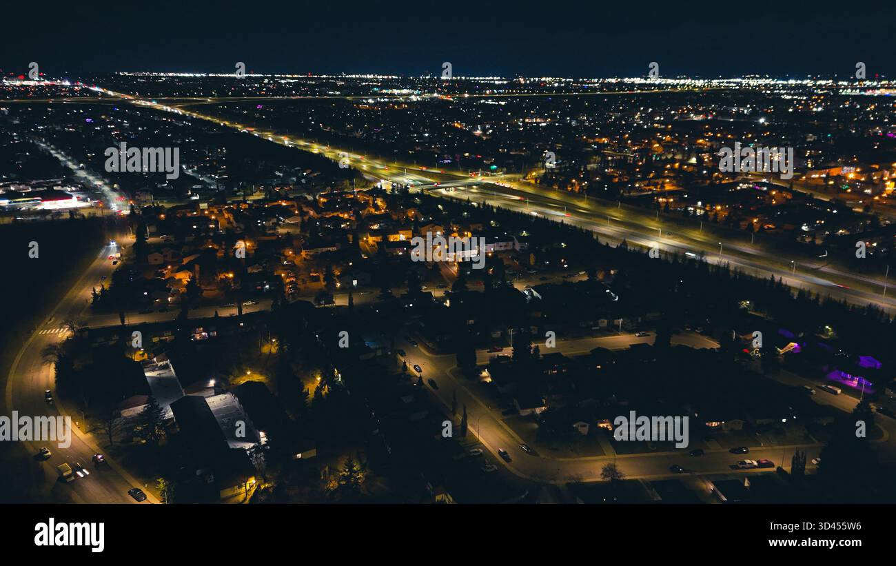 Paesaggio notturno aereo di autostrade illuminate e luci della città che si estendono in lontananza. Foto Stock